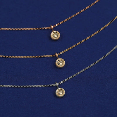 Three versions of the Champagne Diamond Necklace shown in options of yellow, white and rose gold on a dark blue background
