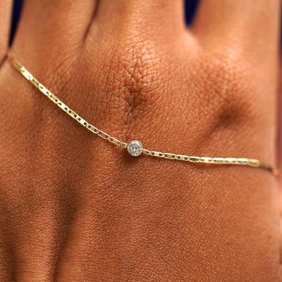 A solid gold Moissanite Bracelet resting on the back of a model's hand