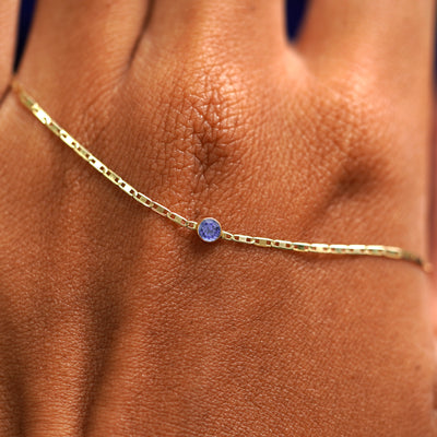 A solid gold Tanzanite Bracelet resting on the back of a model's hand