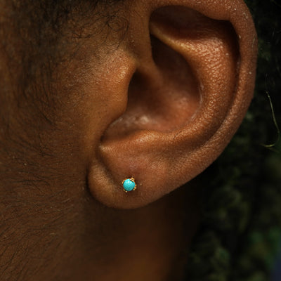 A model's ear wearing a 14k solid gold turquoise 3mm Gemstone Earring