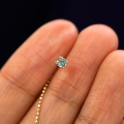 A solid 14k yellow gold aquamarine Gemstone Ear Threader Earring in between a model's fingers