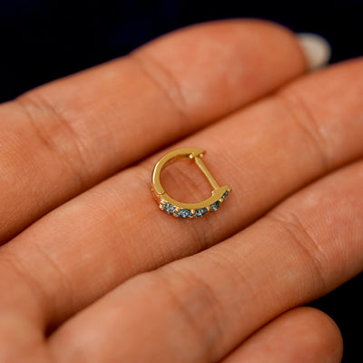 A small Light Blue Lab Diamond huggie hoop earring on a models fingers