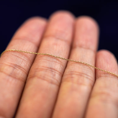 A yellow gold Cable Bracelet resting on a model's fingers