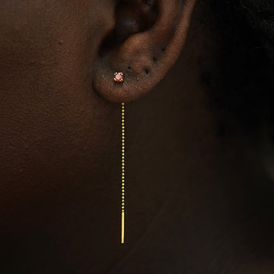 Close up view of a model's ear wearing a 14k gold garnet Gemstone Ear Threader Earring