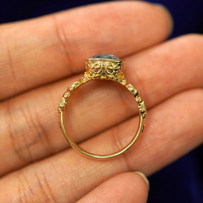 A yellow gold London blue topaz Royalty Ring in a model's hand showing the thickness of the band
