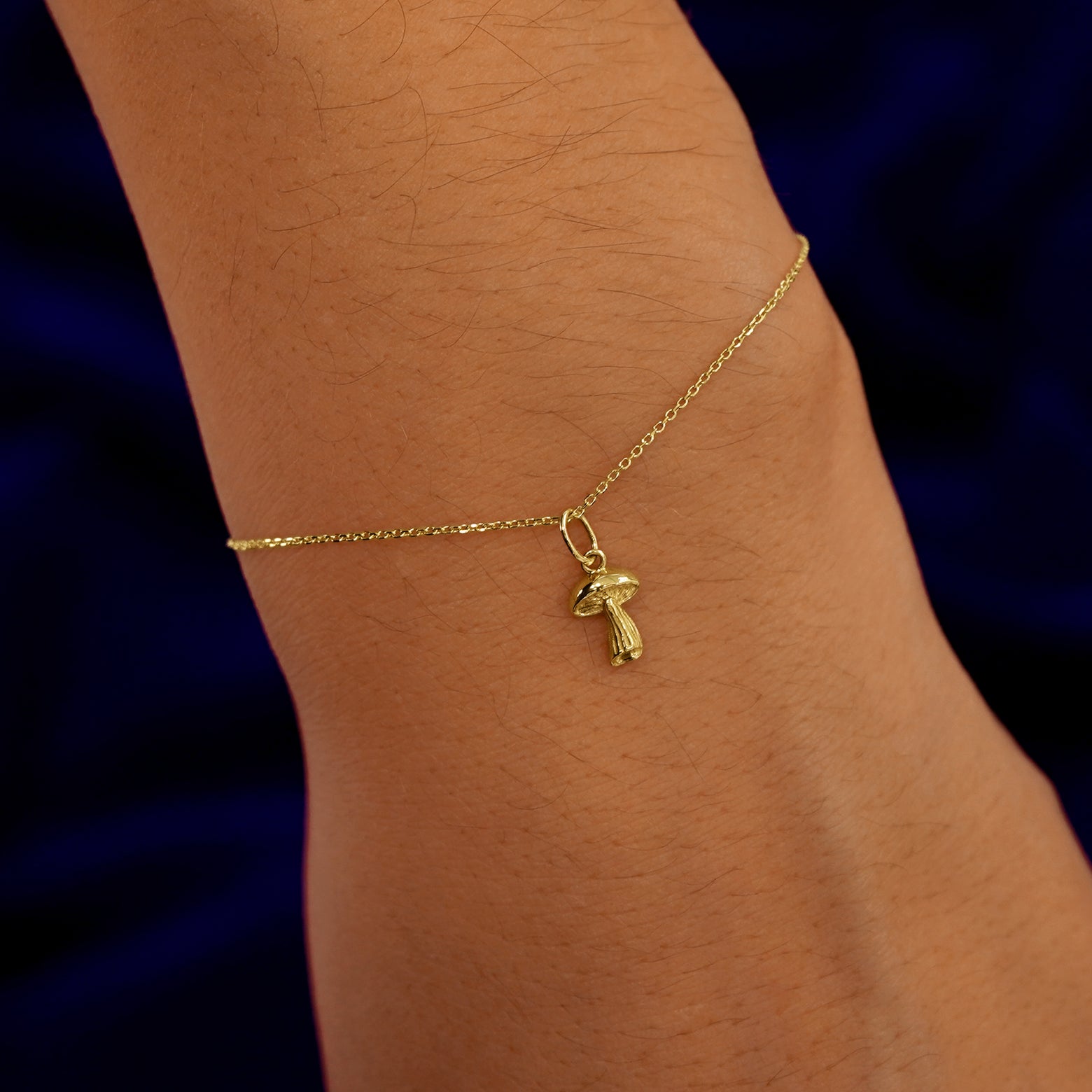 A model's wrist wearing a yellow gold Mushroom Charm on a Cable Bracelet