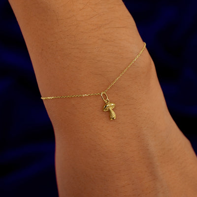 A model's wrist wearing a yellow gold Mushroom Charm on a Cable Bracelet