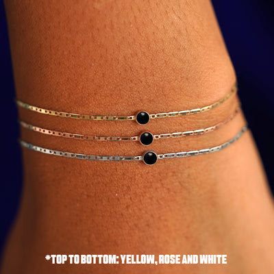 A model's wrist wearing three version of the Onyx Bracelet in options of yellow, white, and rose gold