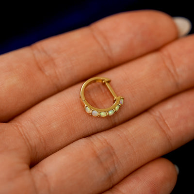 A small Opal huggie hoop earring on a models fingers