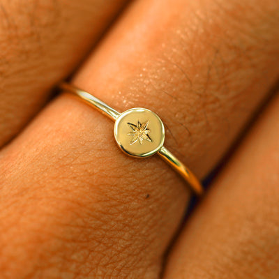 A model wearing a circle disk ring with an engraved star in the center