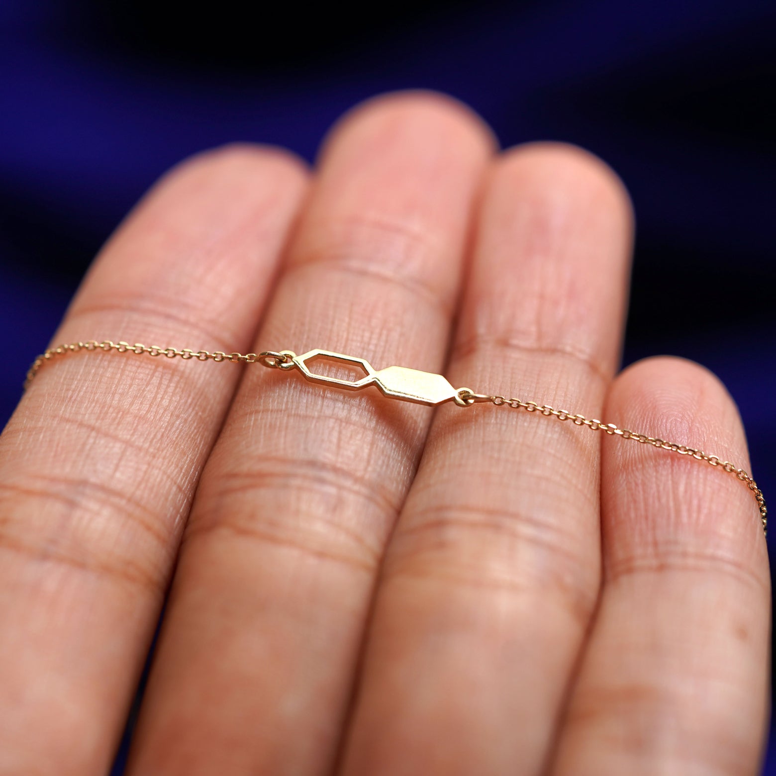 A yellow gold Tanlah Cable Bracelet resting on a model's fingers
