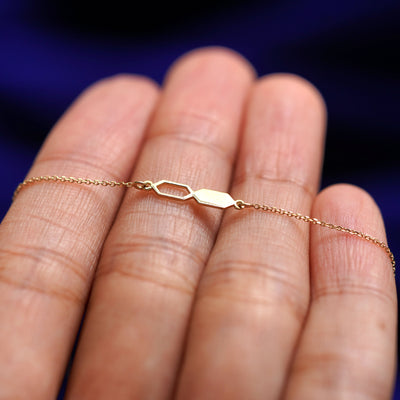 A yellow gold Tanlah Cable Bracelet resting on a model's fingers