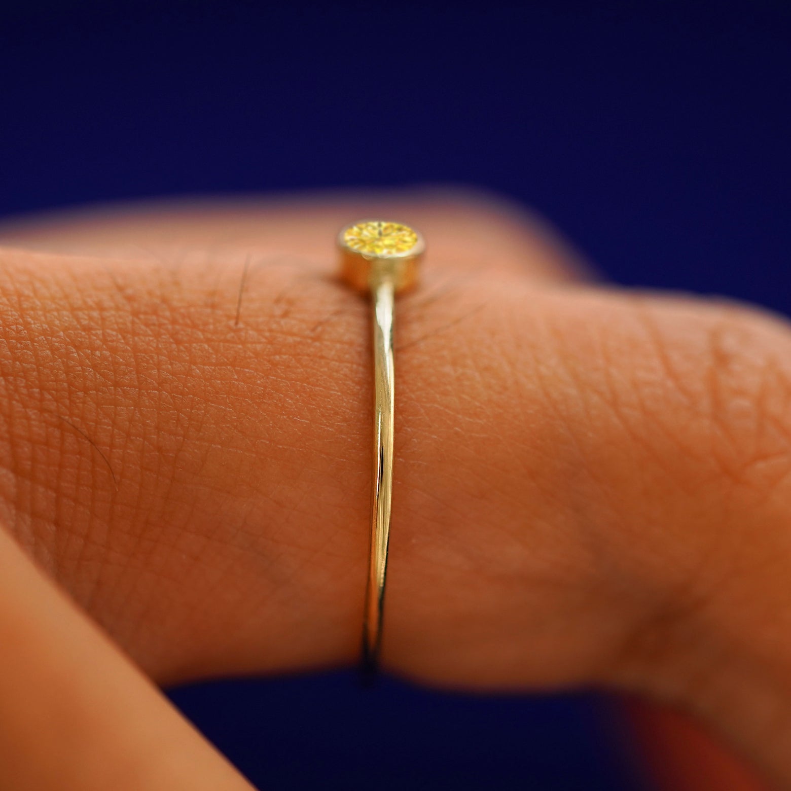 Side view of a solid gold Yellow Diamond Ring on a model's finger