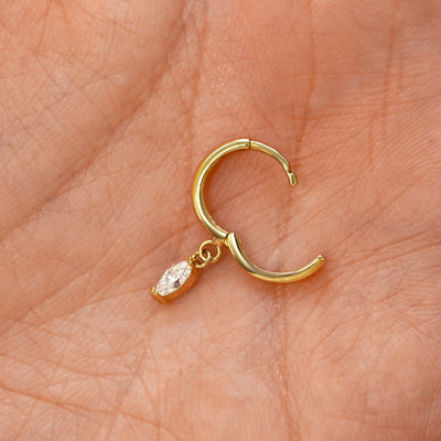 A solid 14k yellow gold Marquise Lab Diamond Dangle Huggie Hoop Earring open in a model's palm