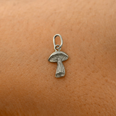 A solid 14k white gold Mushroom Charm resting on the back of a model's hand