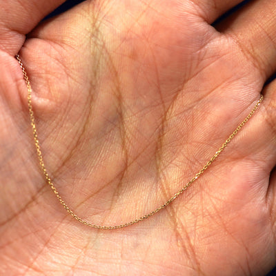 A yellow gold Cable Bracelet draped on a model's palm