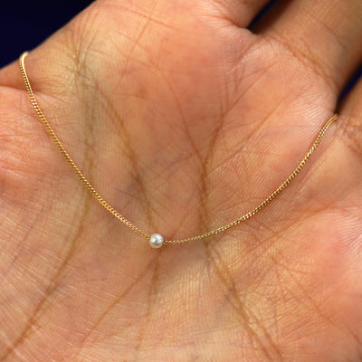 A 2mm pearl slide necklace draped on a model's palm