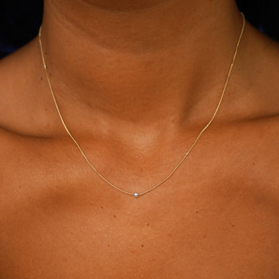 A model's neck wearing a yellow gold Pearl Slide Necklace with a 2mm pearl
