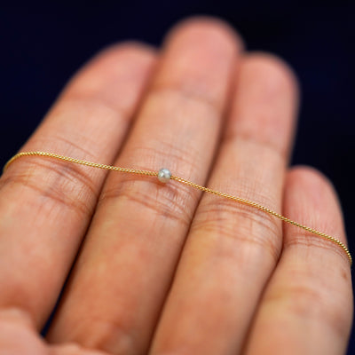 A 2mm pearl slide necklace resting on a model's fingers