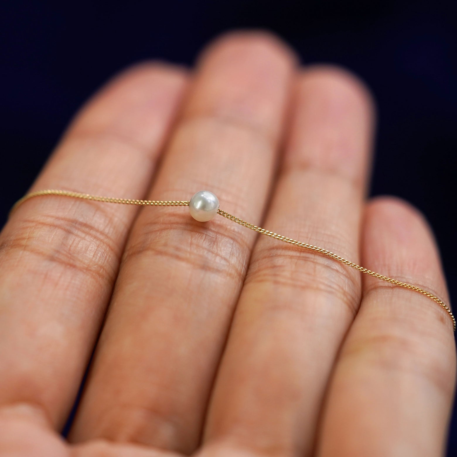 A 4mm pearl slide bracelet resting on a model's fingers