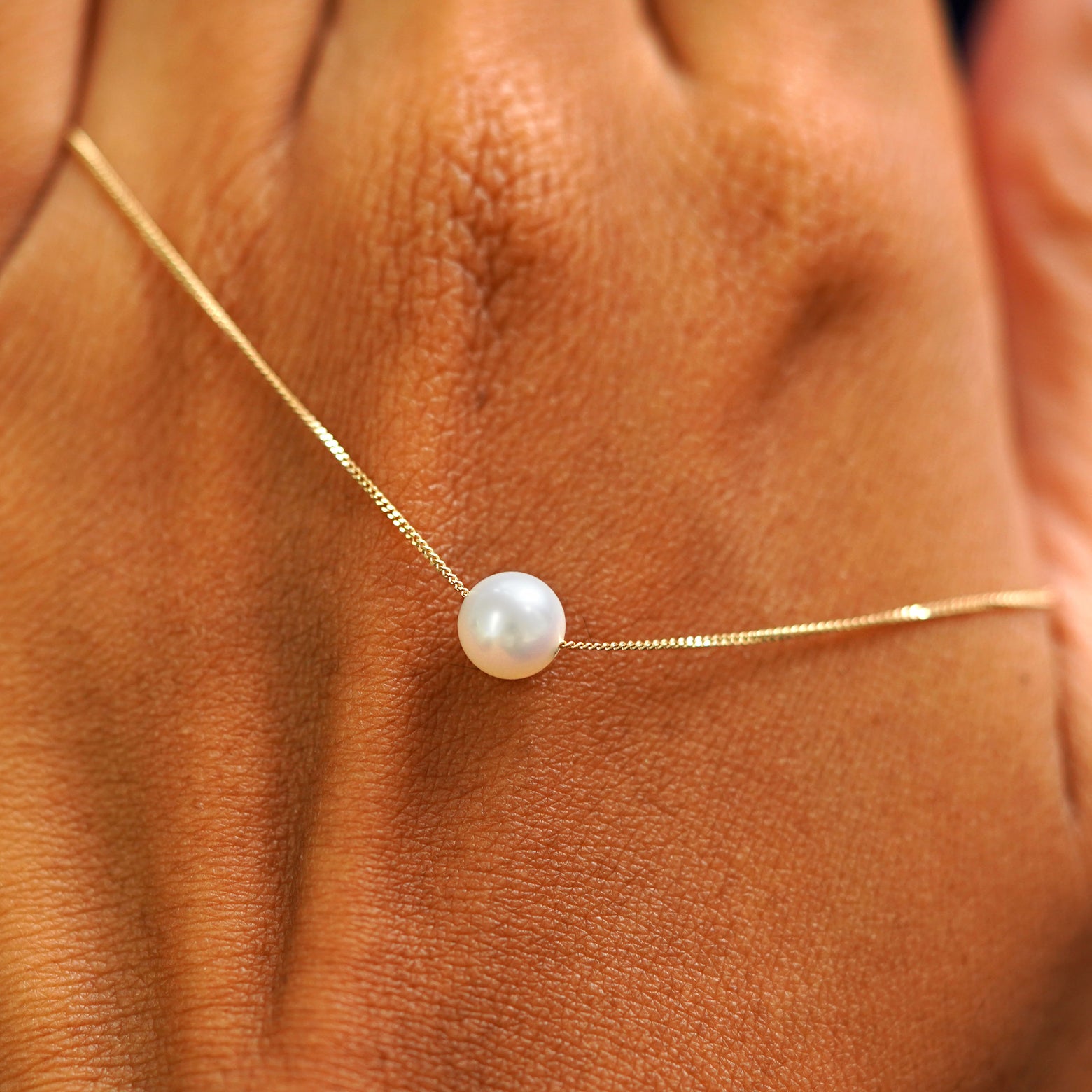 A 6mm pearl slide necklace resting on the back of a model's hand
