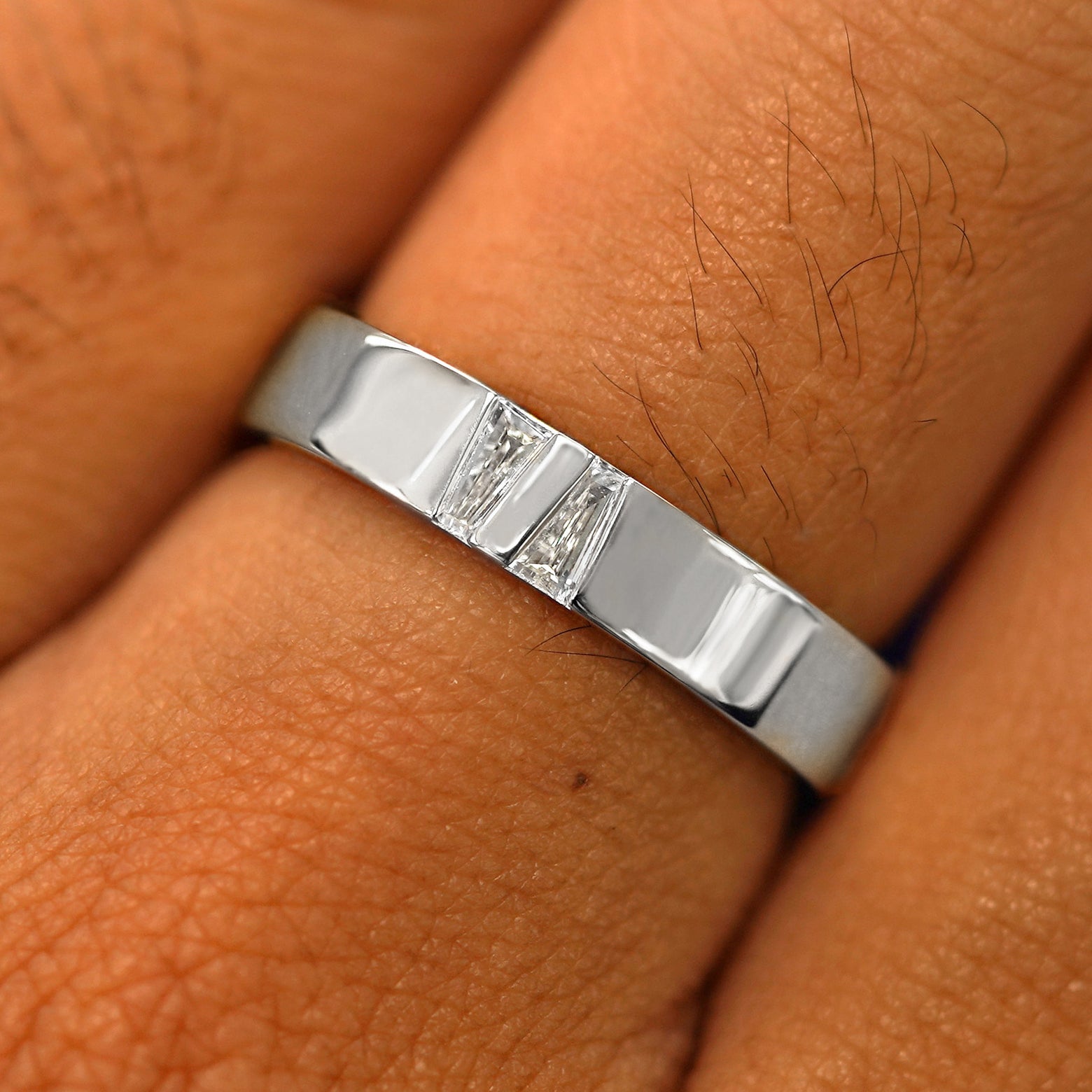 Close up view of a model's hand wearing a solid platinum Double Baguette Diamond Band