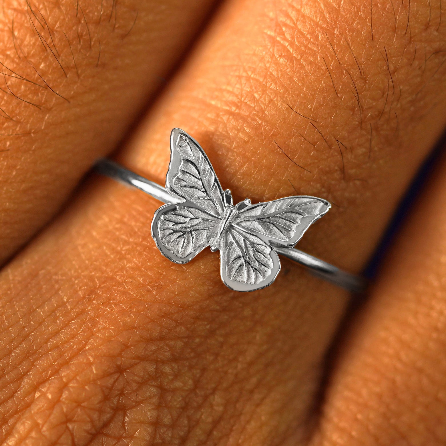 Close up view of a model's fingers wearing a platinum Butterfly Ring