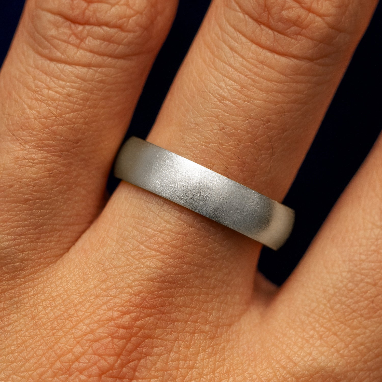 Close up view of a model's fingers wearing a 4mm 950 Platinum Curvy Matte Band