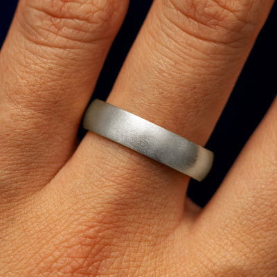 Close up view of a model's fingers wearing a 4mm 950 Platinum Curvy Matte Band