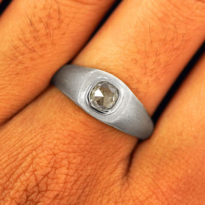 Close up view of a model's fingers wearing a 950 platinum Cushion Salt and Pepper Diamond Signet Ring