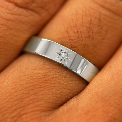 Close up view of a model's hand wearing a solid platinum Engraved Star Diamond Band