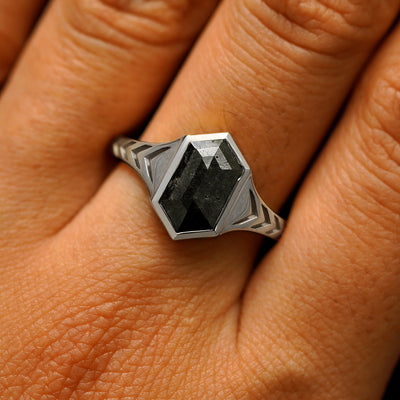 Close up view of a model's fingers wearing a 950 platinum elongated hexagon black diamond engraved chronos ring