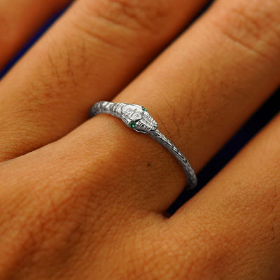 Close up view of a model's hand wearing a platium emerald Gemstone Ouroboros Snake Ring