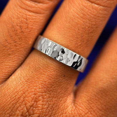 Close up view of a model's fingers wearing a 4mm platinum Industrial Hammered Band