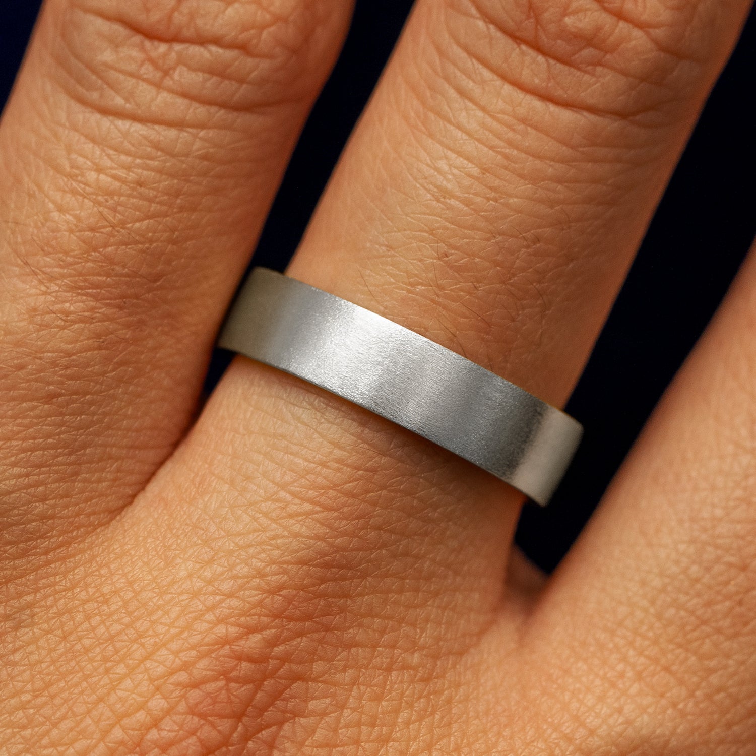 Close up view of a model's fingers wearing a 4mm 950 platinum Industrial Matte Band
