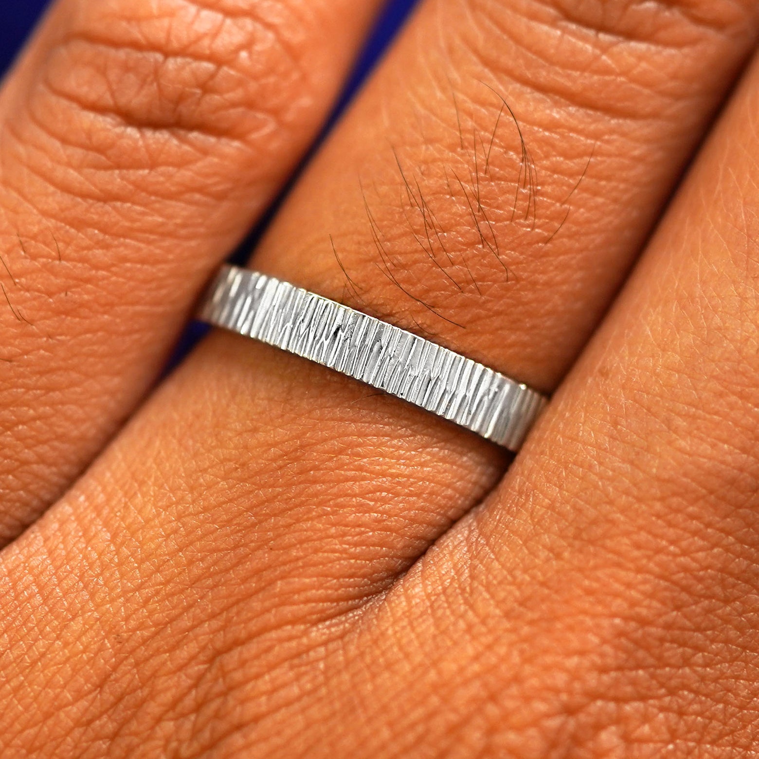 Close up view of a model's fingers wearing a 2mm platinum Industrial Wood Band