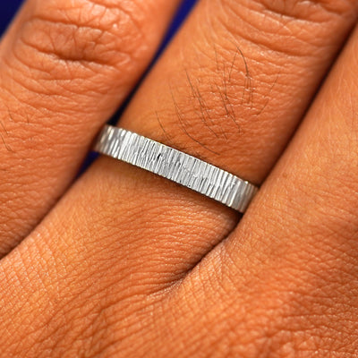 Close up view of a model's fingers wearing a 2mm platinum Industrial Wood Band
