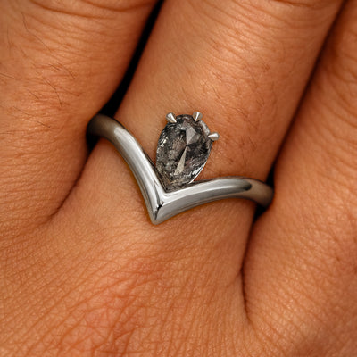 A model's hand wearing a 950 platinum Pear Salt and Pepper Diamond Chevron Ring