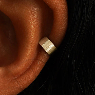 Close up view of a model's ear wearing a 14k champagne gold Stardust Thick Cuff