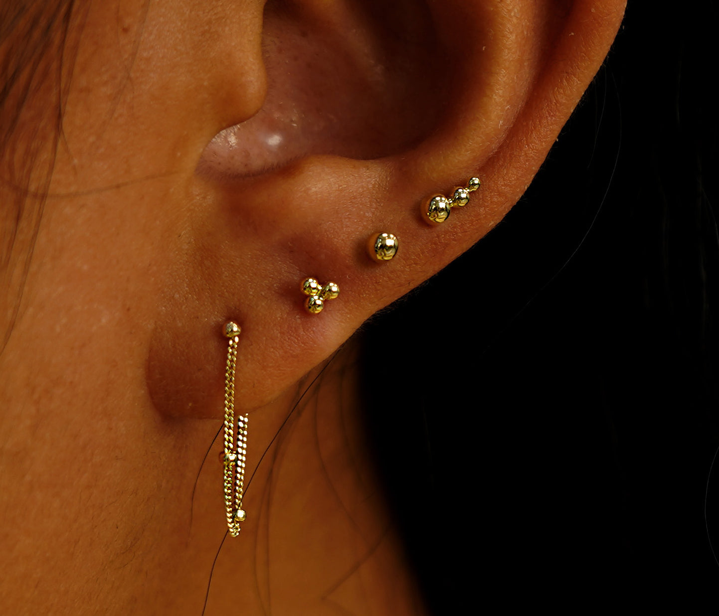 A model's ear wearing four pieces from our Ball Jewelry collection in different piercings