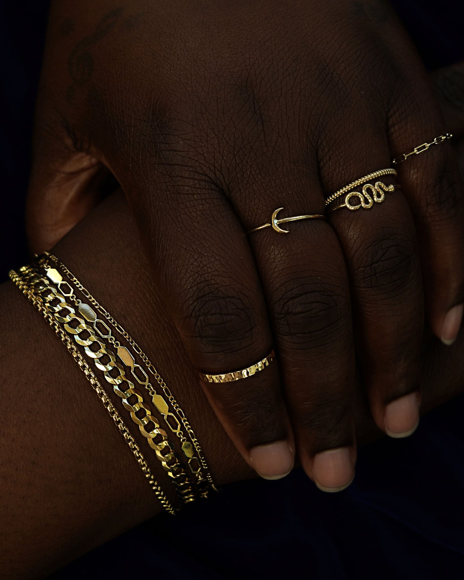 A models with their hands posed one of the other wearing Automic Gold rings and chain bracelets in yellow gold