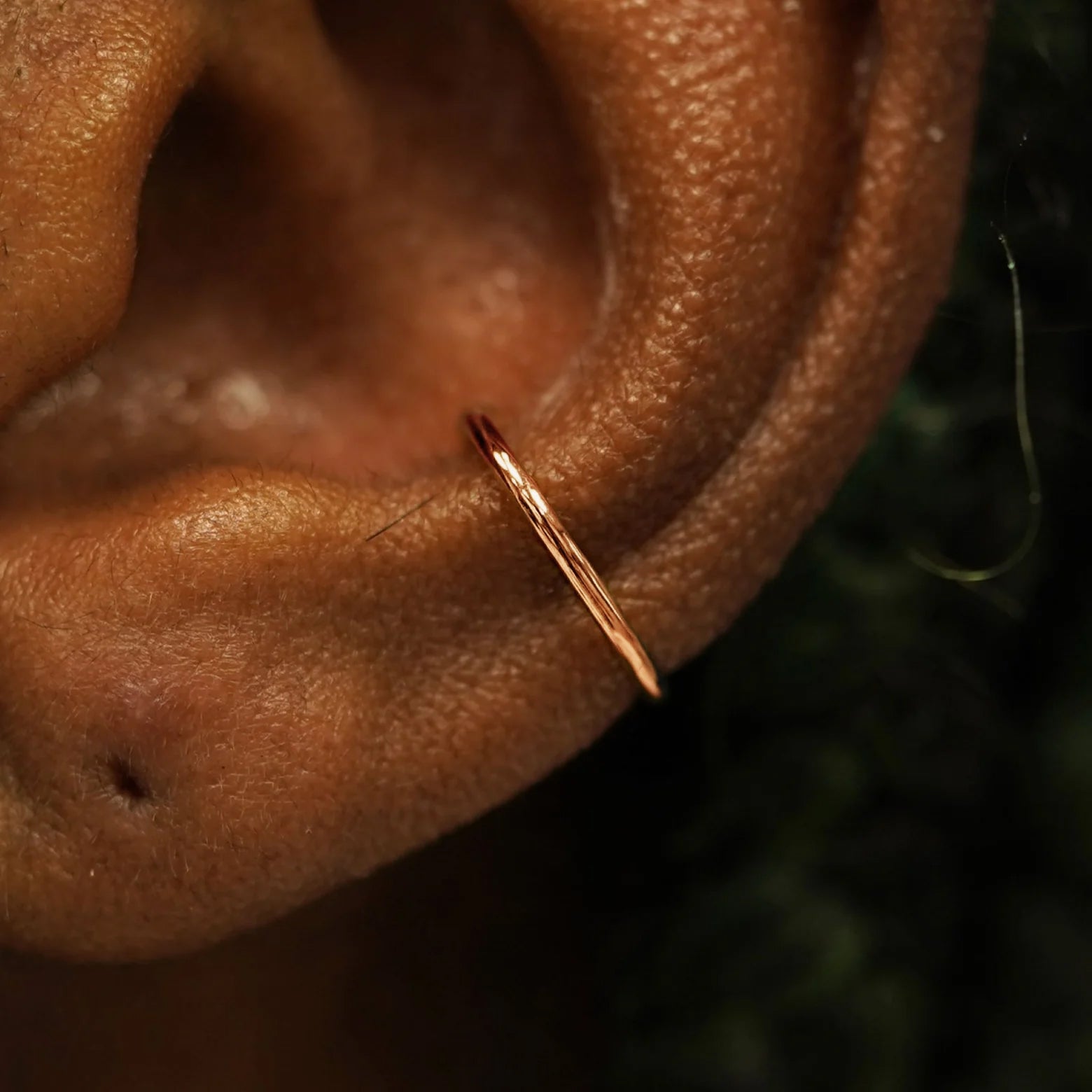 Close up view of a model's ear wearing a solid 14k rose gold Line Cuff