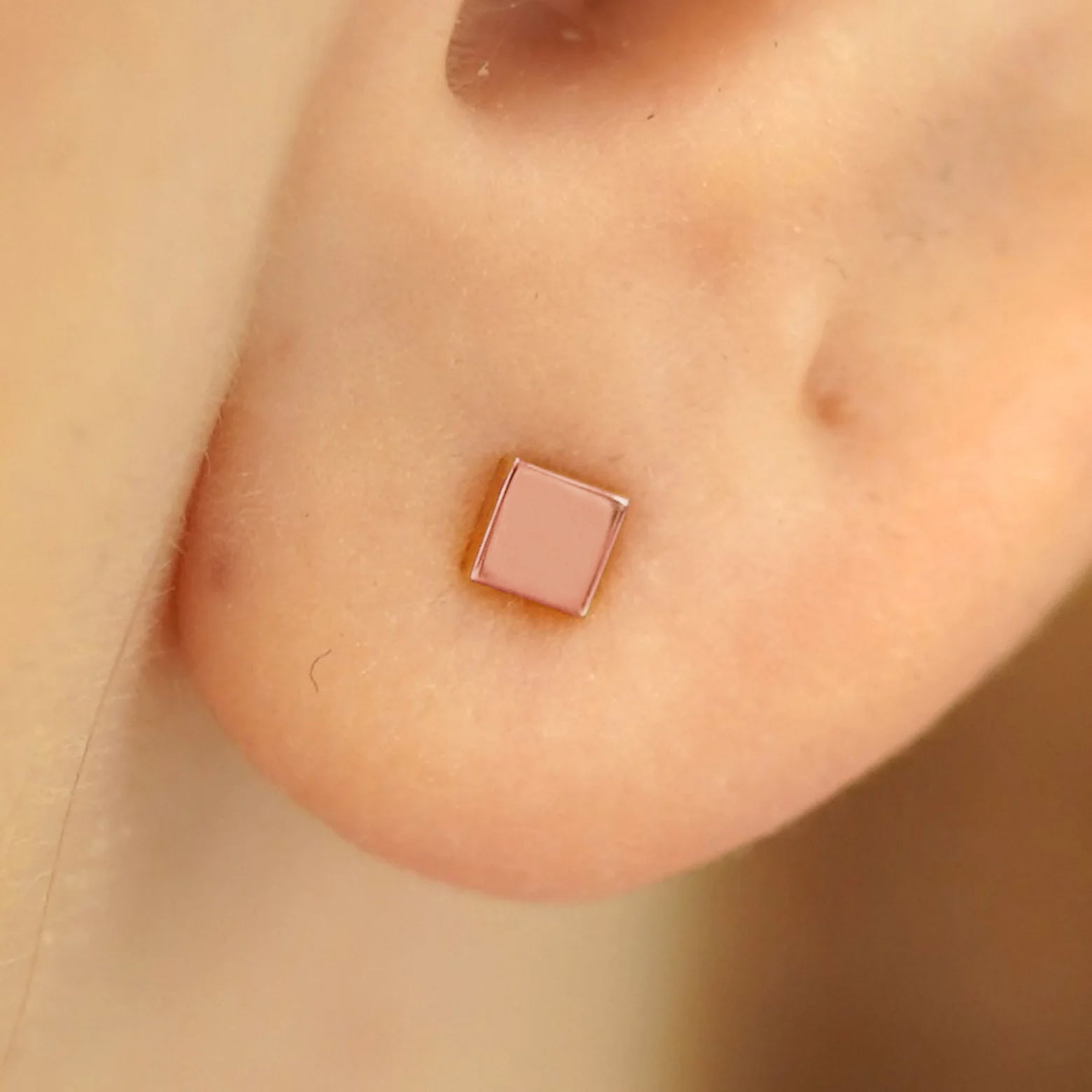 Close up view of a model's ear wearing a 14k rose gold Square Earring