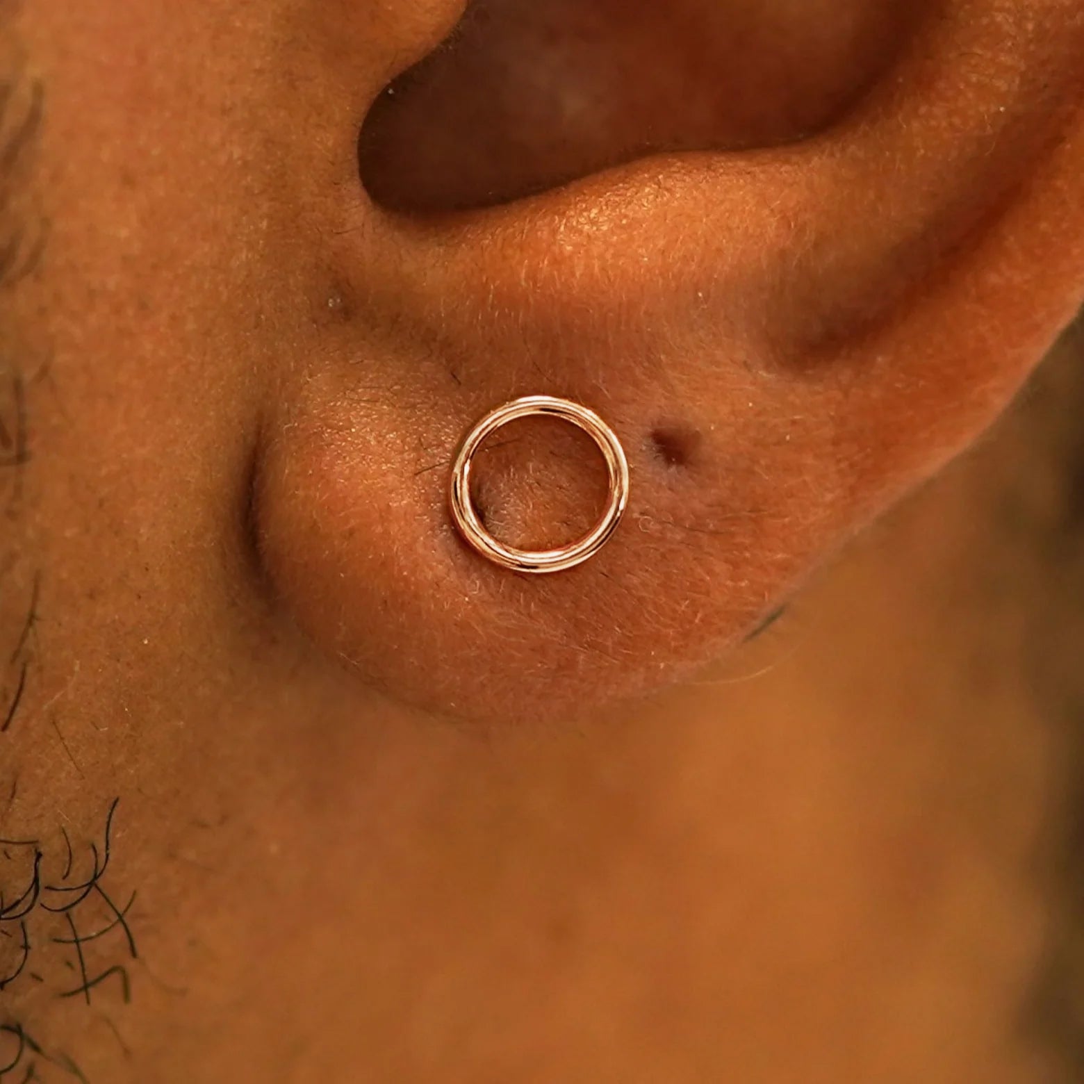 Close up view of a model's ear wearing a 14k rose gold Open Circle Earring