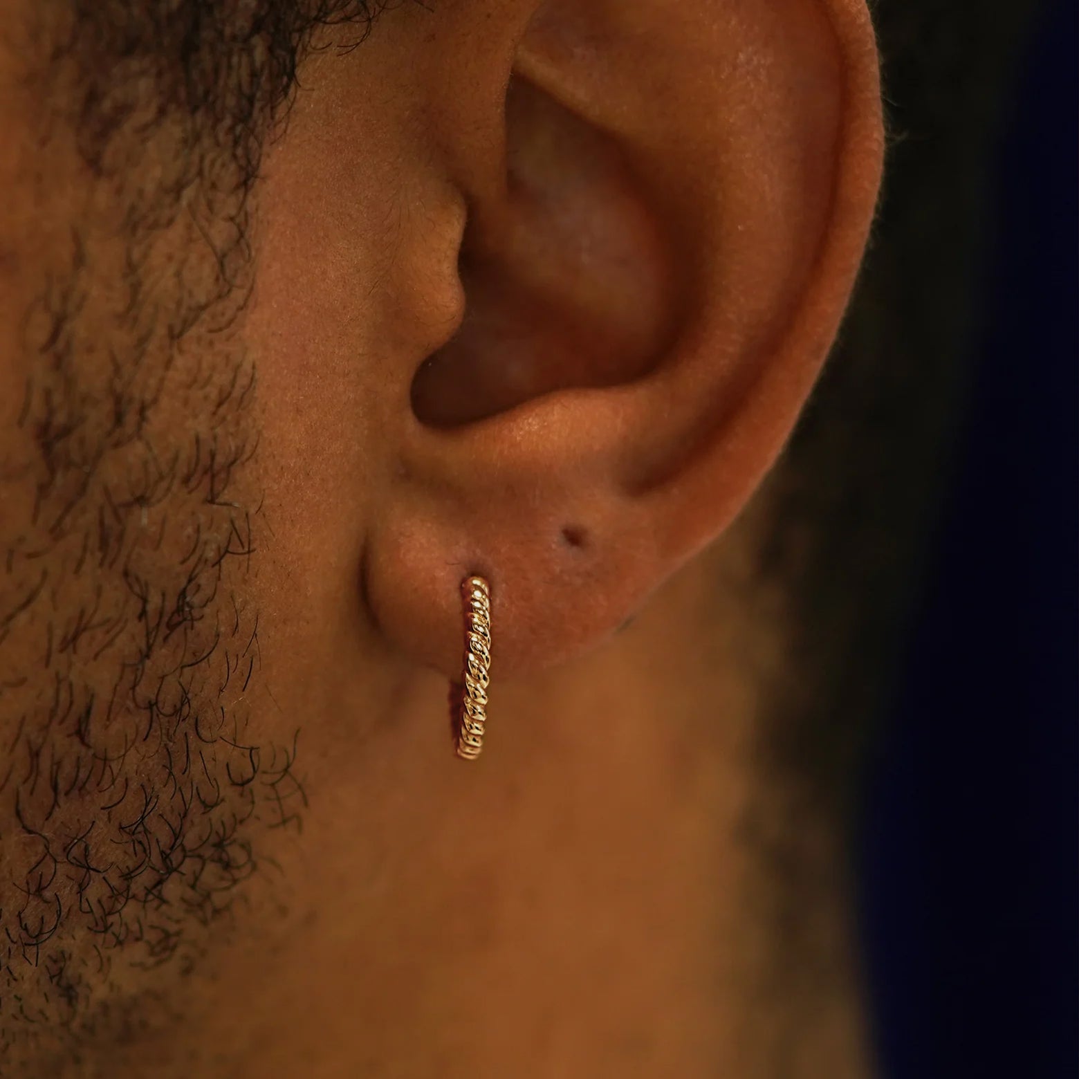 Close up view of a model's ear wearing a rose gold Medium Rope Huggie Hoop