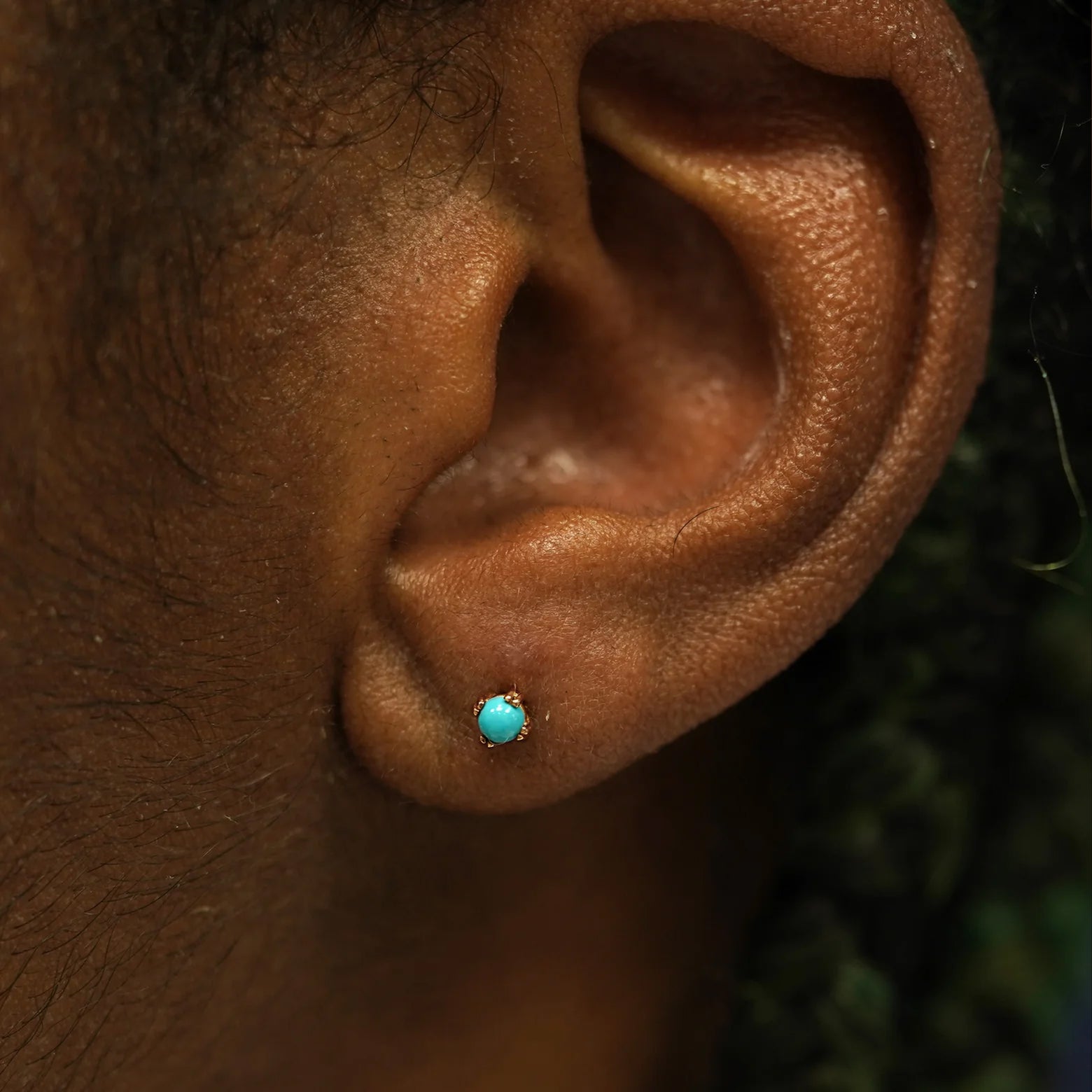 Close up view of a model's ear wearing a 14k rose gold turquoise 3mm Gemstone Earring