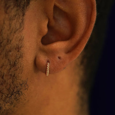 A model's ear wearing a 14k rose gold Mini Rope Huggie Hoop Earring