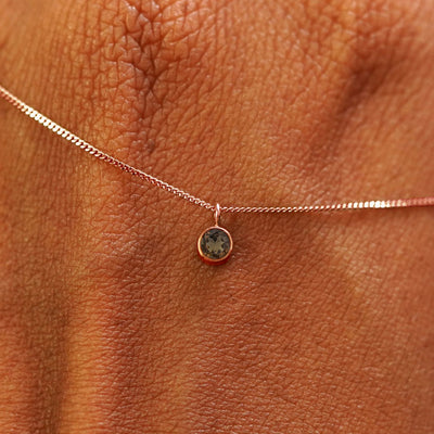 Close up view of a 14k rose gold Smoky Quartz Necklace draped across the back of a model's hand