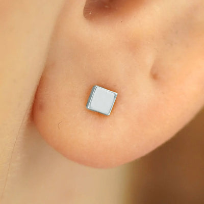 Close up view of a model's ear wearing a 14k white gold Square Earring
