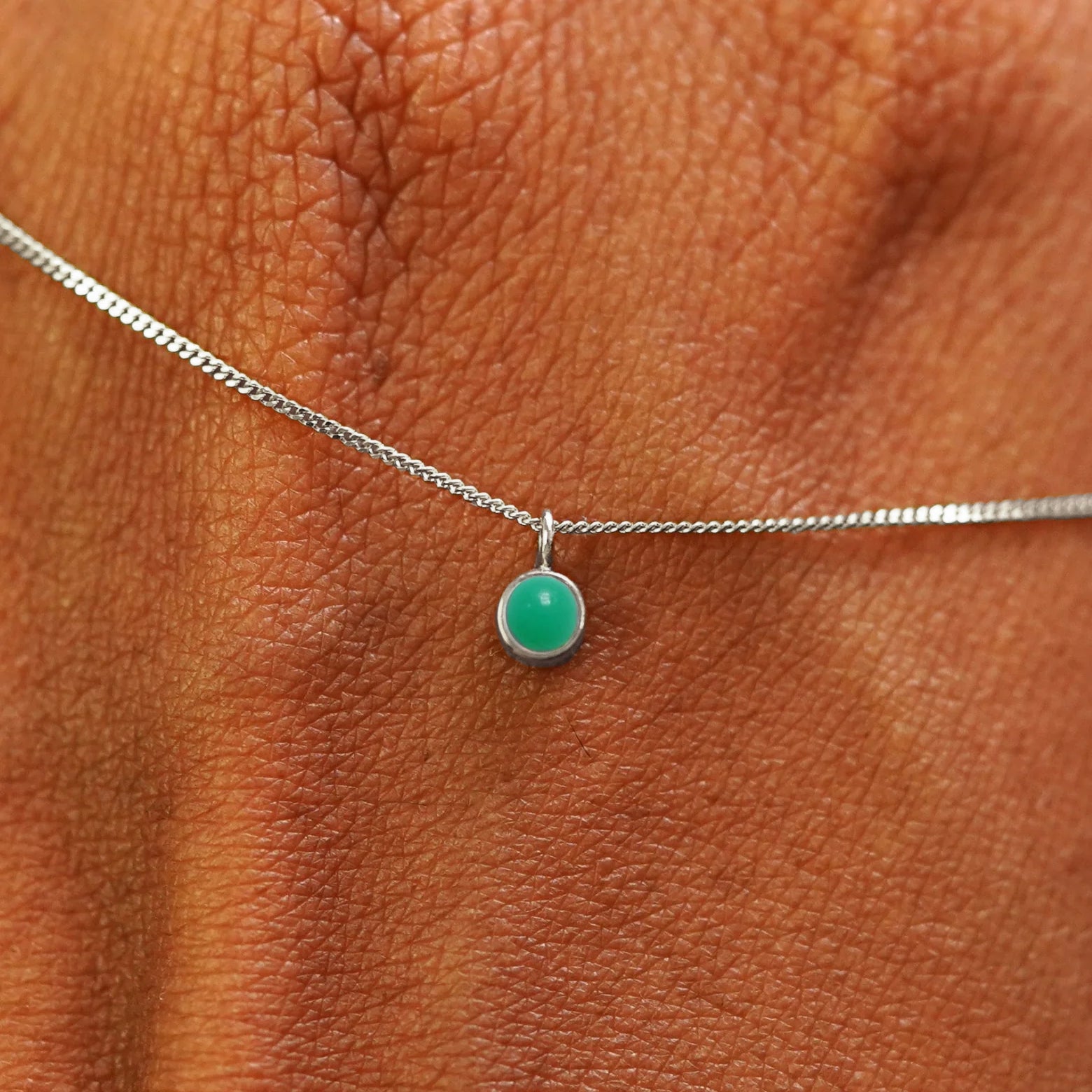 Close up view of a 14k white gold Jade Necklace draped across the back of a model's hand